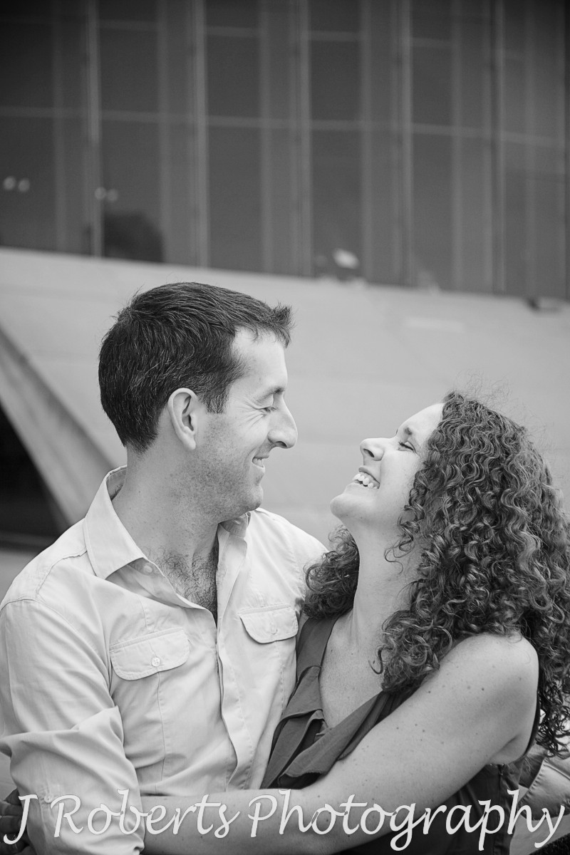 Couple laughing together on Sydney Opera House forecourt - engagement photography sydney
